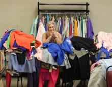 ECU business student Emilia Smith poses behind a pile of recently donated designer clothes.