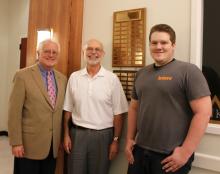 Stephen Decker (right), a student at East Central University, stands by the plaque that includes his name as the 2012 winner of ECU’s prestigious Adolph Linscheid Award for speech and debate students.