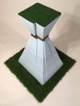 This is a photograph of Leticia Bajuyo’s creation “Tighten Your Belt: Ranch” made of cast iron, Styrofoam, artificial grass, steel and adhesive.