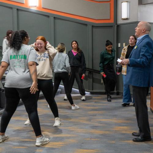 Pairs of students stand opposite each other wit ha red cup on the ground in between them, listening to Eric Smith explain the activity.