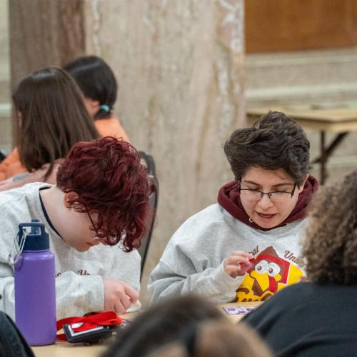 Two students scan their bingo cards waiting for their numbers to be called out.