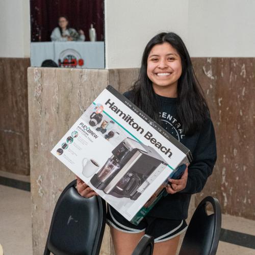 A student poses with her new coffee machine after winning a round of bingo.