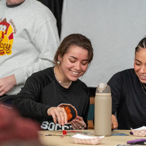 Two students laugh with each other while playing bingo.