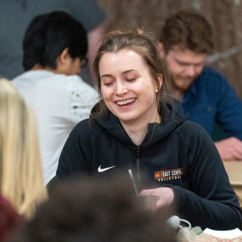 A student laughs while playing bingo with her friends.